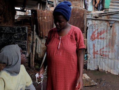 A pregnant Kenyan girl, 17, talks with her younger sister outside their home in Lindi, near Nairobi, in November 2020.