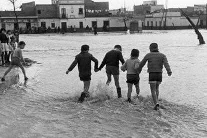 Unos niños juegan en 1961 en el cruce de las actuales Ronda del Tamarguillo y calle Paulo Orosio con el barrio del Cerro del Águila, en una foto de la muestra.