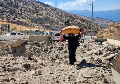 Una mujer traslada sus pertenencias entre un socavón de un proyectil israelí en el paso fronterizo de Masnaa, en Líbano, este viernes.