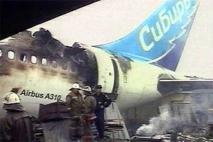 Un grupo de bomberos observa los restos del avión siniestrado.