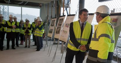 Feij&oacute;o, en el centro, saluda a un responsable de las obras del hospital de Vigo durante una visita.