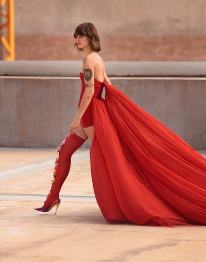 Sánchez lleva vestido de gasa de Giambattista Valli; medias de encaje rojo con flores de Adriana Hot Couture; y zapatos Ribbon D’Orsay con cinta fina y punta con detalle dorado, de Gianvito Rossi. Anillos de cóctel de las colecciones Surprises y Exquises y colgante de la colección Bee my Love en oro blanco engastado con diamantes, todo de Chaumet.