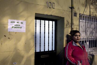 Una joven ante una casa de Trinitat Vella en la que un cartel especifica que no tienen nada que ver con el mundo de la droga.