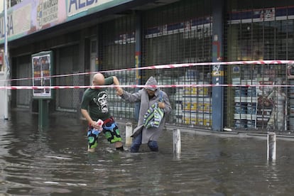 Dos personas intenta cruzar una de las calles inundadas en Buenos Aires. El temporal produjo desbordes de ríos, daños a viviendas y alumbrado público