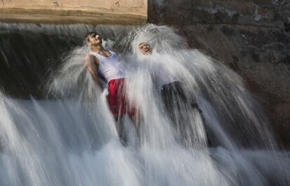 Dos hombres se bañan para combatir el calor en las afueras de Islamabad, Pakistán.