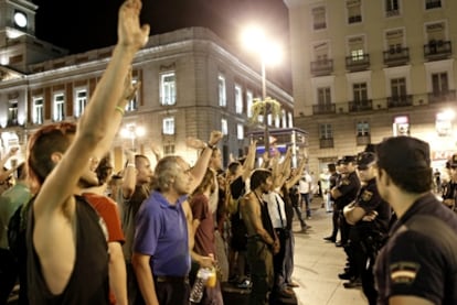 Un grupo de indignados se encara con la policía, que previamente había pedido la documentación a unos manteros, poco antes de la asamblea de medianoche en Sol.