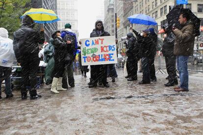 Un manifestante que participa en Occupy Wall Street se mantiene en una calle mientras comienza a caer la tormenta de nieve que ha cubierto el noreste de EE UU. La pancarta dice: "No puedo enviar a los niños a la universidad".