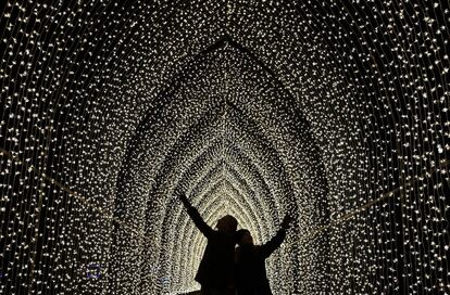 Dos jóvenes caminan entre un sendero iluminado en Kew Gardens de Londres con motivo de la Navidad.