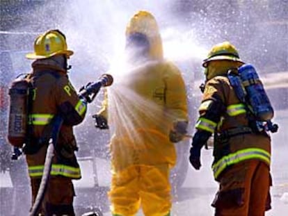 Dos especialistas en tratamiento de materiales peligrosos desinfectan a un compañero en Temple Hills (Maryland)