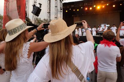 Dos mujeres toman vídeo mientras los organizadores del festival hablan en el escenario