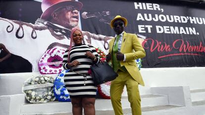 Dos miembros de la subcultura urbana &#039;sapeur&#039;, frente a un cartel de Papa Wemba este lunes en Abiy&aacute;n (Costa de Marfil). 