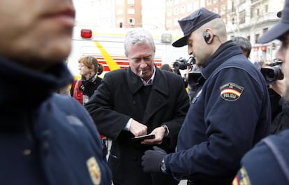 Jorge Verstrynge is asked for his ID card by police officers outside the home of Deputy PM Soraya Sáenz de Santamaría.