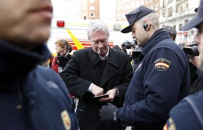 Jorge Verstrynge is asked for his ID card by police officers outside the home of Deputy PM Soraya S&aacute;enz de Santamar&iacute;a.