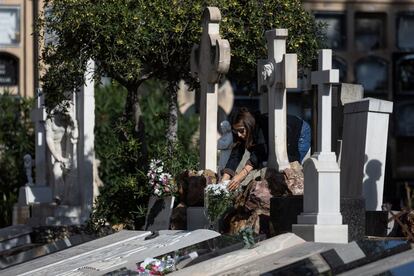 Una mujer coloca flores en una tumba en el cementerio de les Corts, este lunes en Barcelona. 