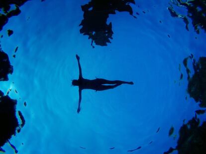 Una mujer vista desde abajo flotando en una piscina de Madrid.