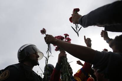 Pessoas oferecem flores a um policial na entrada de um centro esportivo.