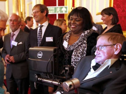 Stephen Hawking junto a su enfermera, Patricia Dowdy, durante una visita a Isabel II en el Palacio de Buckingham en 2014.