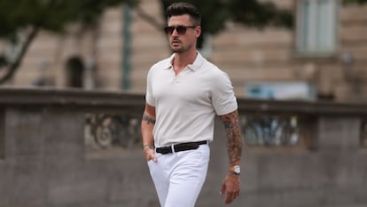 Un hombre paseando por la calle con un polo beige.