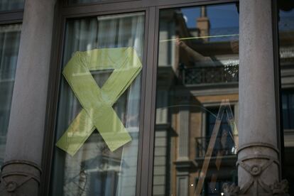 Un empleado de la Conselleria de Economía trabaja en el interior del edificio junto a un lazo amarillo expuesto en una de las ventanas de su fachada, este jueves.