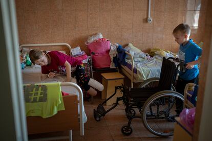 Yarik ayuda a su hermana gemela en la habitación del hospital público de Lviv.  Yarik resultó ileso en el mismo bombardeo donde su hermana y su madre resultaron gravemente heridas.  