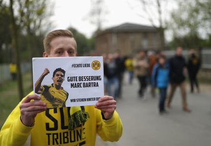 Un aficionado del Borussia de Dortmund sostiene una pancarta en apoyo a Marc Bartra, herido en el ataque que sufrió el autobús del equipo alemán junto a su hotel de concentración.