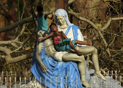 Dos ni&ntilde;os filipinos juegan con una estatua de la Virgen Mar&iacute;a en Bulan (Filipinas), tras el paso del tif&oacute;n Melor. Al menos una persona ha muerto y 733.000 m&aacute;s tuvieron que ser evacuadas debido al tif&oacute;n Melor, que desde ayer azota la regi&oacute;n central del pa&iacute;s.