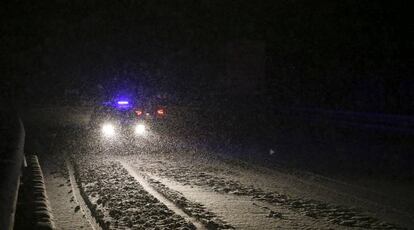 Un veh&iacute;culo de emergencias transita por una carretera nevada,