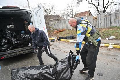 Dos civiles ucranios trasladan cadáveres asesinados por las tropas rusas en Bucha, el domingo. Un equipo de reporteros de la agencia de noticias France Presse ha sido testigo en las calles de la ciudad, a unos 30 kilómetros al noroeste de Kiev, de la devastación provocada por los soldados rusos, que el jueves se retiraron de la localidad, en la que se han hallado los cadáveres de más de 300 civiles.