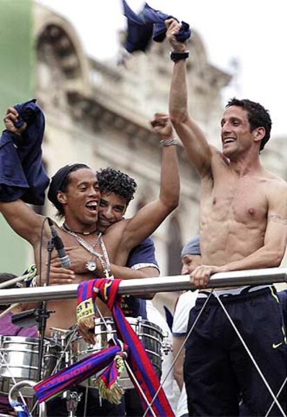 Ronaldinho, abrazado por Rijkaard, y Belletti bailan en el desfile del equipo por las calles de Barcelona.