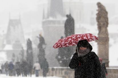 Una mujer camina por el puento de Carlos de Prague, bajo una fuerte nevada.