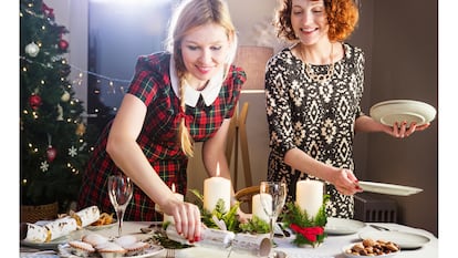 Dos mujeres ponen la mesa para una celebración navideña.