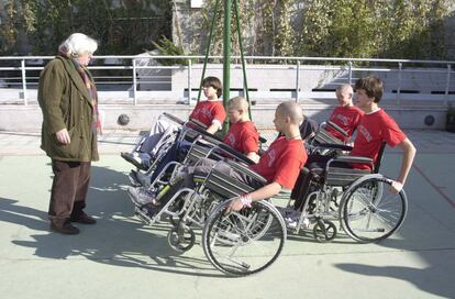 El director Antonio Mercero (i) dirigiendo a varios actores en sillas de ruedas durante el rodaje del filme 'Los pelones (Planta 4ª)' en una cancha de baloncesto.  