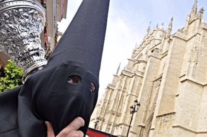 <b>LUNES SANTO. Sevilla.</b> Un nazareno de la Hermandad de Santa Genoveva pasa cerca de la Catedral, poco antes del comienzo de la estación de penitencia de la hermandad.