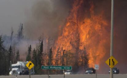 Llamaradas de fuego rozan detrás de multitud de vehículos que se han visto obligados a evacuar la zona.