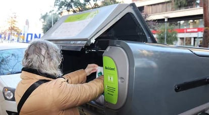 Una mujer deposita basura en uno de los nuevos contenedores habilitados en Girona.