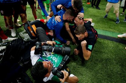 Los jugadores de la selección de fútbol croata celebran la victoria frente a la selección de Inglaterra tras tirar al suelo al fotógrafo Yuri Cortez, en el estadio Luzhniki de Moscú (Rusia), el 11 de julio de 2018.