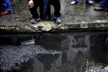 Un activista del sindicato comunista PAME reflejado en un charco durante una protesta organizada en el marco de la huelga general de 24 horas, en Atenas (Grecia).