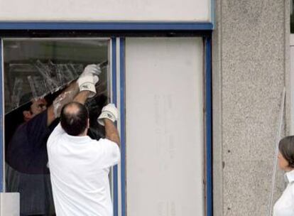 Dos vecinos reparan los daños sufridos en su vivienda por la explosión del coche bomba.