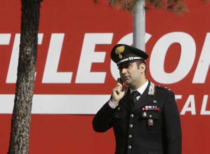 Un <i>carabiniere</i> habla por su teléfono móvil a las puertas de la sede de Telecom Italia en la ciudad de Rozzano.