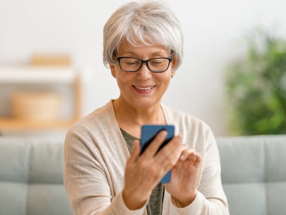 Una mujer mayor utilizando un móvil en su casa.