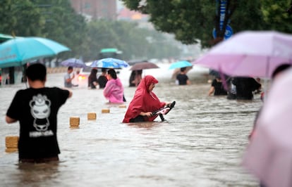 Gente caminando por una carretera inundada de Zhengzhou, en la provincia central china de Henan, el martes 20 de julio de 2021.