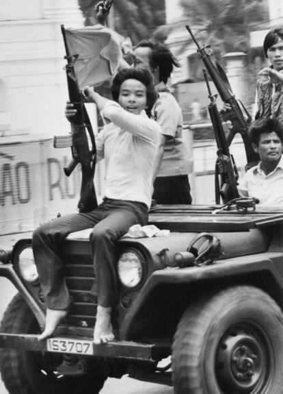 Jovem segura arma e bandeira do Governo Revolucionário Provisório em uma rua de Saigon, em 4 de maio de 1975.