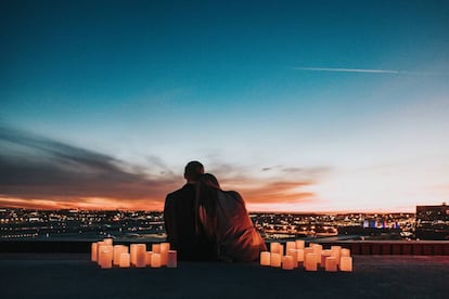 Una pareja observa el atardecer rodeada de velas.