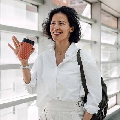 Un mujer camino de su trabajo tomando un café.