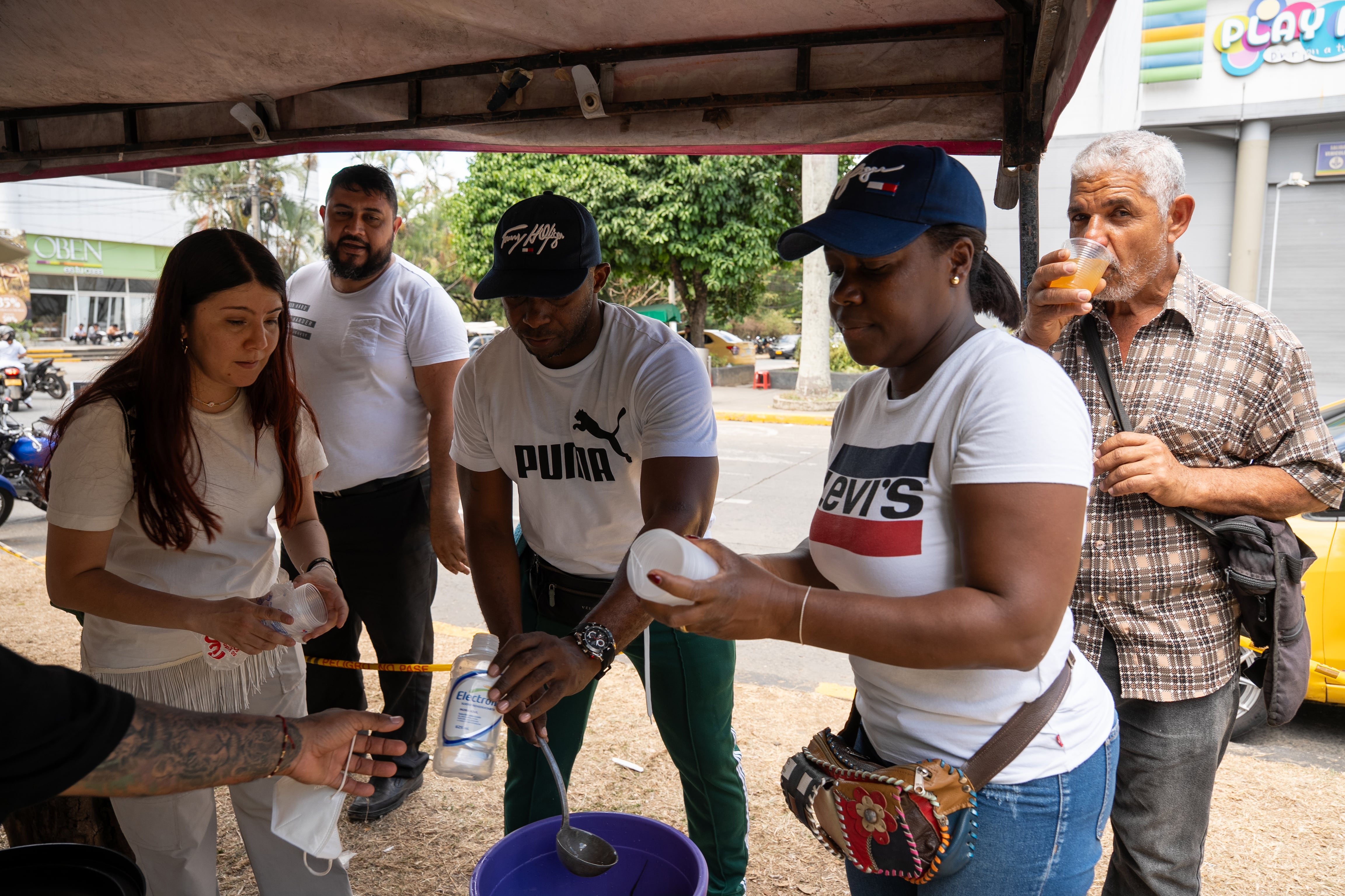 Neiber Moreo y su esposa, Alexa Mena, sirven limonada como voluntarios en una zona afectada por el terremoto en Cali.