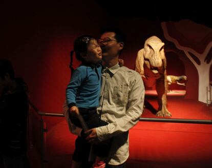 Un padre consuela a su hija después de ver un modelo interactivo de Tyrannosaurus rex, durante una exposición de dinosaurios en Hong Kong (China), el 9 de abril de 2014.