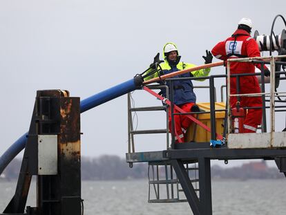 Dos trabajadores despliegan un cable de fibra óptica entre las islas alemanas de Rügen y Hiddensee, en febrero de 2022.