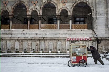 Un vendedor ambulante empuja su carrito por una calle nevada en Estambul (Turquía), el 31 de diciembre de 2015.