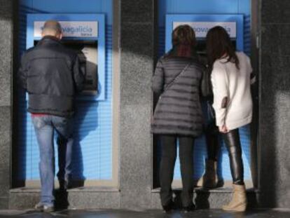 Personas sacan dinero de una sucursal bancaria.