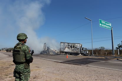 Un soldado hace guardia ante los restos de un vehículo quemado en la carretera, en Mazatlán (Sinaloa), este jueves.